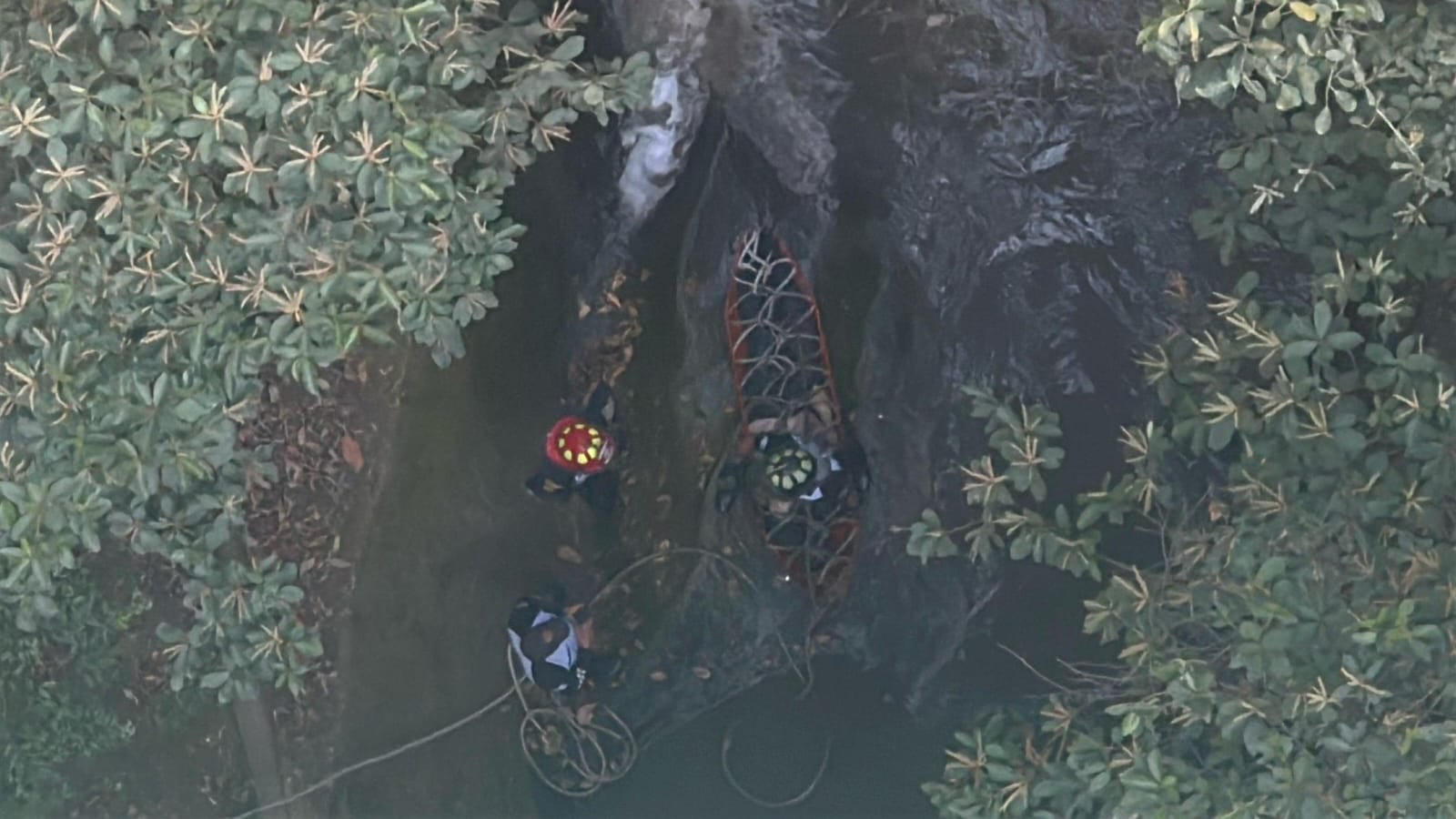 Cuerpo de Bomberos Voluntarios rescata el cuerpo al fondo de un río de aguas negras.