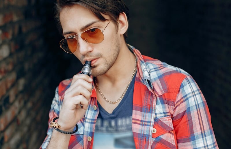 Hombre con estilo y elegante en una ciudad con vape