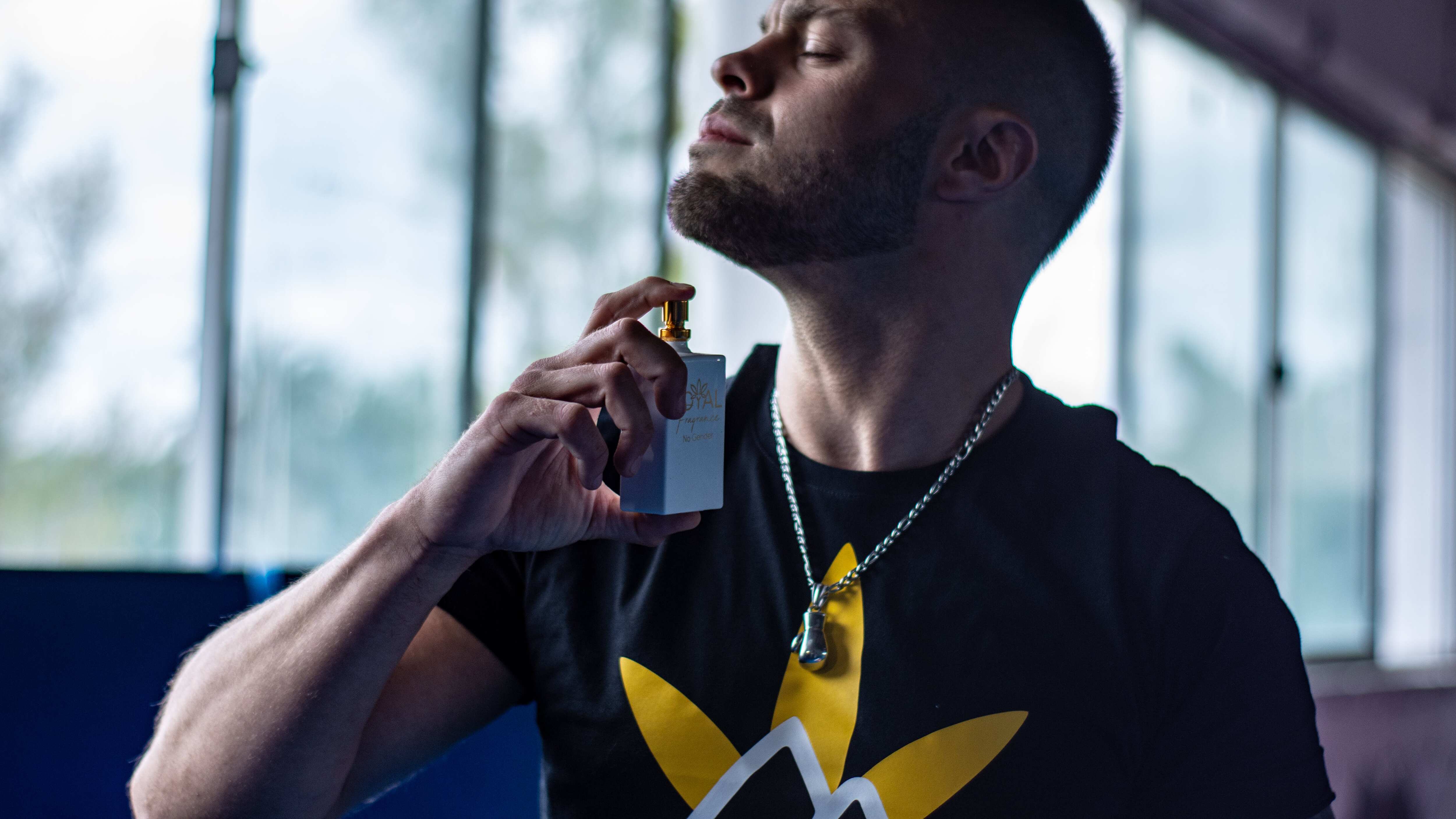 Homem espirrando perfume no pescoço